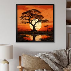 a painting on the wall of a living room with a tree and water at sunset