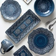 a table topped with blue and white plates and silverware next to utensils