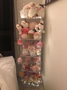 a shelf filled with lots of stuffed animals on top of it's sides next to a bed