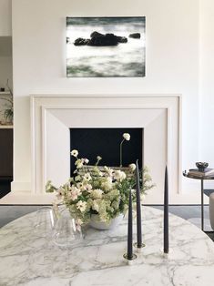 a table with flowers and candles on it in front of a fireplace