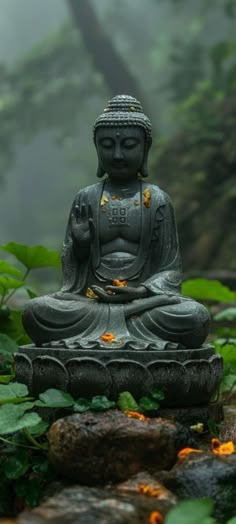 a buddha statue sitting on top of a lush green field next to rocks and trees