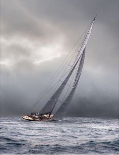 a sailboat sailing in the ocean on a cloudy day with dark clouds above it