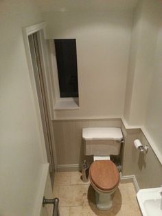 a bathroom with a toilet, sink and window in the corner on the right side