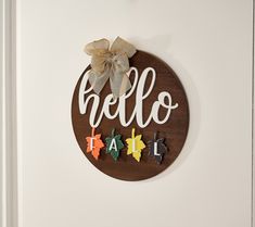 a wooden sign that says hello fall hanging on the wall next to a white door