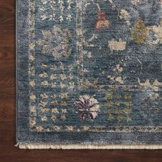 a blue rug with floral designs on the top and bottom, sitting on a wooden floor