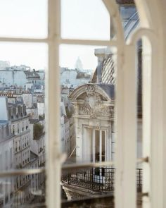 the view from an open window looking at buildings