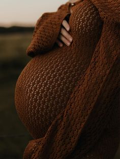 a pregnant woman wrapped in a brown sweater