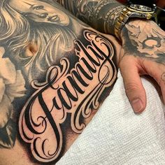 a tattooed man's arm with the word family on it and his name in cursive writing