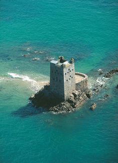 an old stone tower sitting on top of a rock outcropping in the ocean