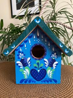 a blue birdhouse sitting on top of a wooden table next to a potted plant