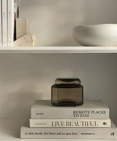 two books are stacked on top of each other in front of a bowl and vase