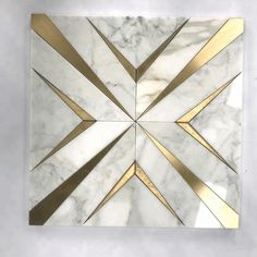 a white marble wall with gold lines in the shape of an abstract geometrical design