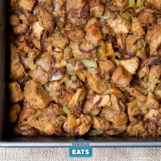 a casserole dish with meat and vegetables in it sitting on a cloth covered table