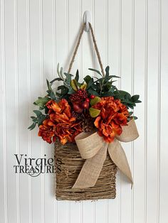 an orange flower arrangement hanging on a wall with burlocks and twine ribbons