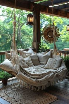 a hammock hanging from the ceiling on a porch with pillows and pillows in it