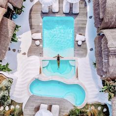 an aerial view of a pool with umbrellas and palm trees