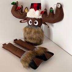 a stuffed moose wearing a santa hat and scarf on top of a white countertop