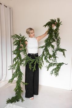 a woman is holding some green plants in her hands