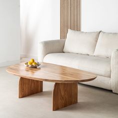 a wooden table sitting in front of a white couch next to a bowl of fruit