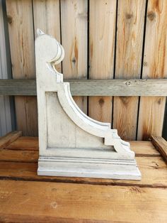 a wooden bench with a white carved design on the top and bottom part, against a wood paneled wall