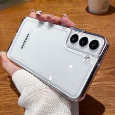 a person holding a clear samsung phone case on their left hand, with three black buttons in the middle