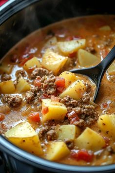 a ladle full of stew with potatoes and meat on the side, ready to be eaten