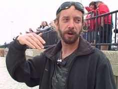 a man is holding something in his hand and looking at the camera while people are standing behind him