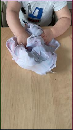 a baby is playing with some cloth on the table