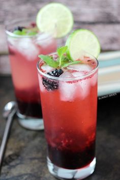 two glasses filled with liquid and garnish sitting on top of a table