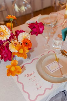 the table is set with colorful flowers and place settings