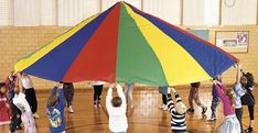 children are playing with a large kite in the gym