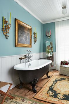 a bath tub sitting next to a window in a bathroom on top of a wooden floor