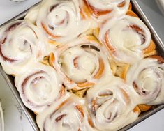 a pan filled with cinnamon rolls covered in icing