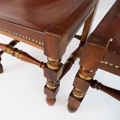 two wooden stools with brass studding on them sitting side by side in front of a white background