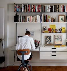 a man sitting at a desk in front of a bookshelf filled with books