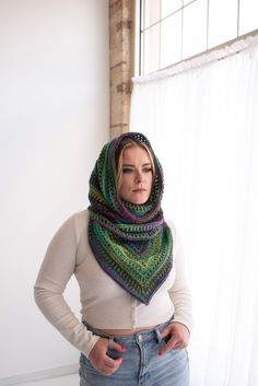 a woman standing in front of a window with her hands on her hips wearing a scarf