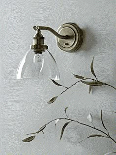 a wall light with a glass shade hanging from it's side next to a plant