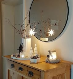 a wooden table topped with two white candles and a mirror over it's top