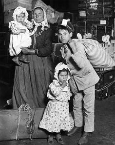 an old black and white photo of three people with two babys in their arms