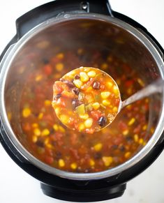 a ladle full of soup with corn and black beans in an instant pressure cooker