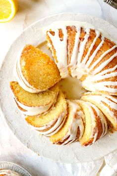 a lemon bundt cake with icing on a plate next to sliced oranges