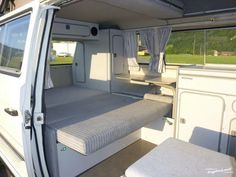 the interior of a camper van with mattresses and storage compartments on the side