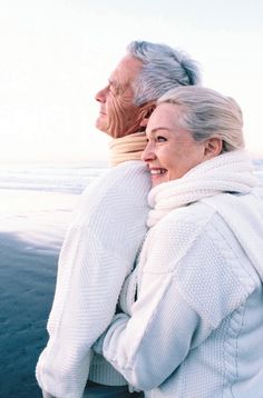 an older man and woman standing next to each other in front of the ocean with a poem written on it