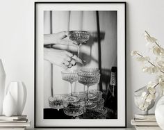 a black and white photo of wine glasses on a shelf with flowers in vases