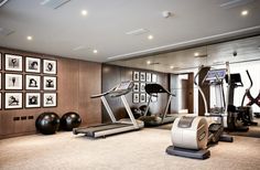 an exercise room with treadmills, machines and pictures on the wall behind it