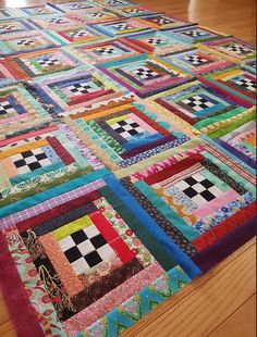 a multicolored patchwork quilt on the floor with wood floors in the background