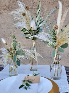 two vases filled with flowers sitting on top of a white tablecloth covered table