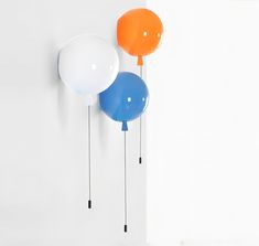 three balloons are hanging on the wall next to each other in different colors and shapes