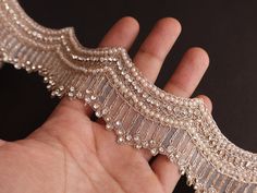 a hand holding a piece of beaded garter