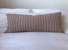 a bed with white sheets and brown striped pillow on it's headrests